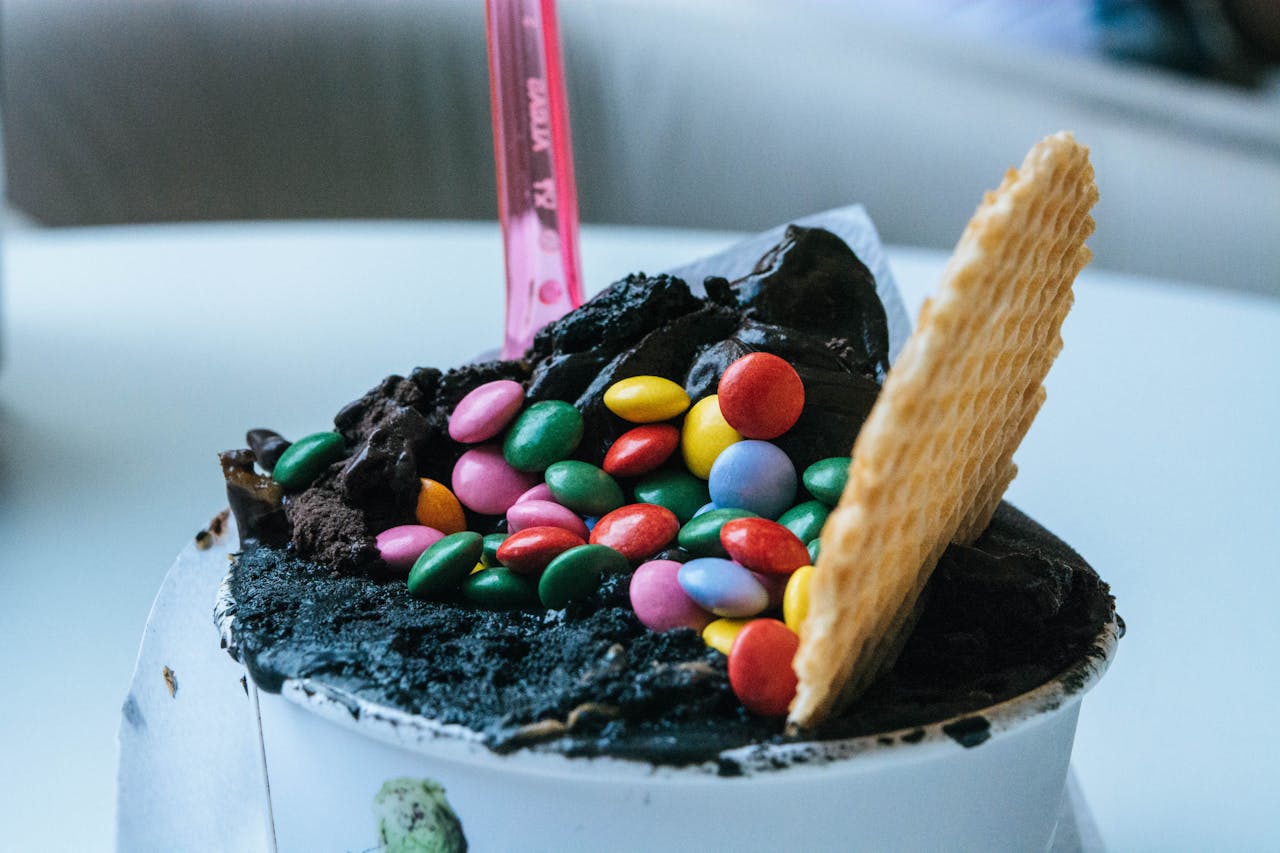 A delicious ice cream cup adorned with colorful toppings and a waffle, perfect for dessert lovers.